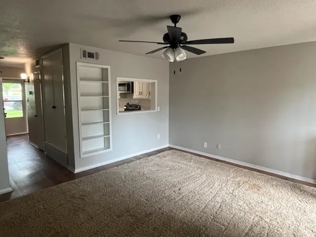 a view of empty room with wooden floor and ceiling fan