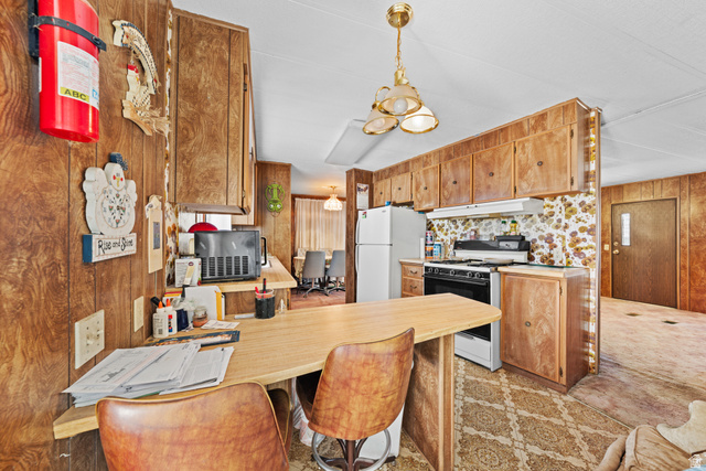 49 600 North Hurricane, UT 84737 - Photo 7 of 33 Kitchen featuring light countertops, a peninsula, white appliances, decorative light fixtures, and a kitchen breakfast bar
