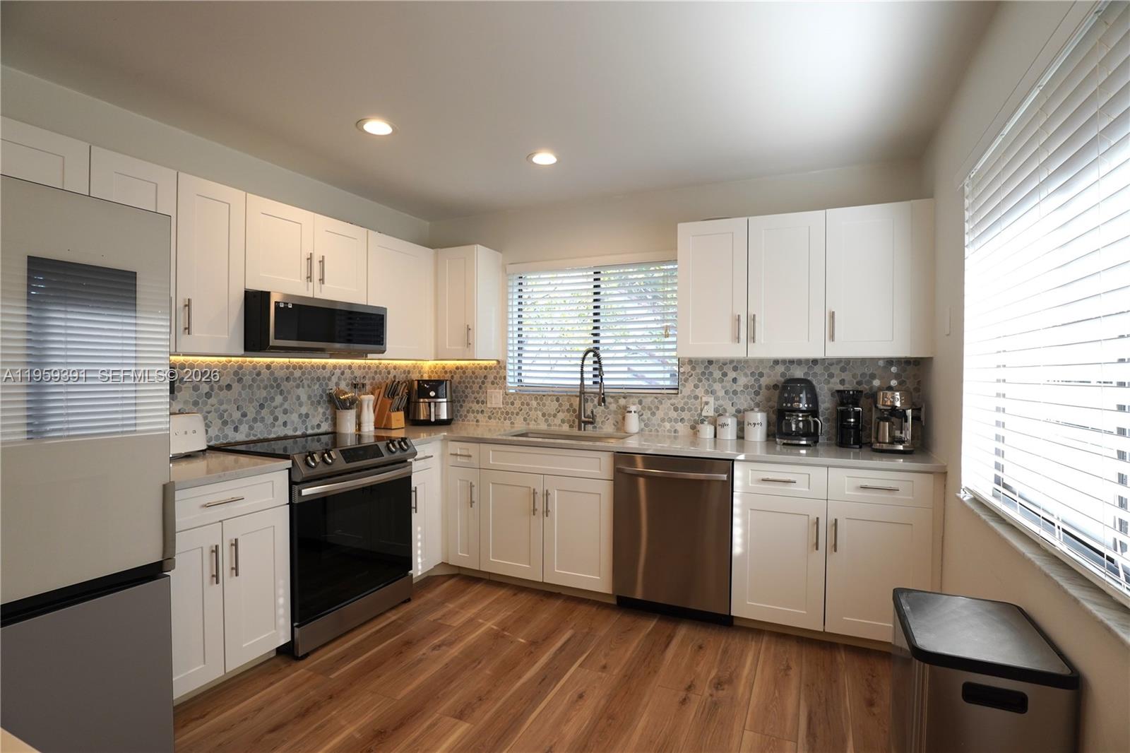 5741 Coach House Circle, Unit H Boca Raton, FL 33486 - Photo 10 of 34 a kitchen with stainless steel appliances granite countertop white cabinets a sink a stove a refrigerator and microwave with wooden floor