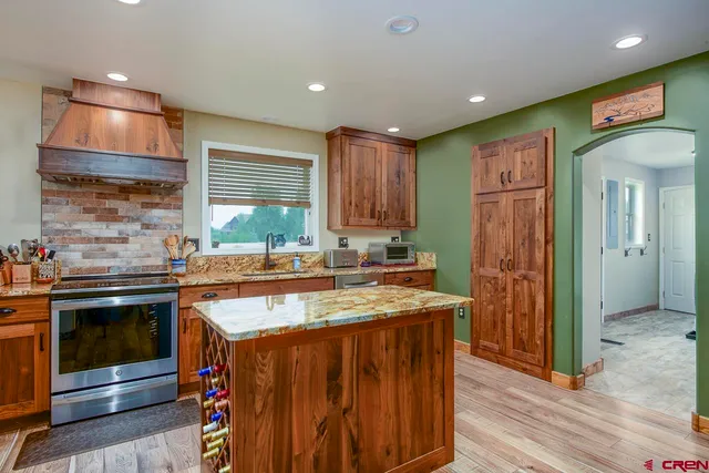 a kitchen with kitchen island granite countertop a sink stove and cabinets