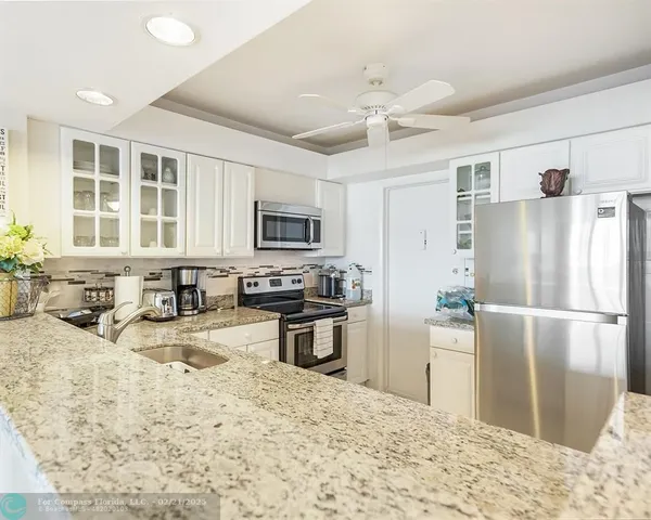 a kitchen with granite countertop a refrigerator stove microwave and sink