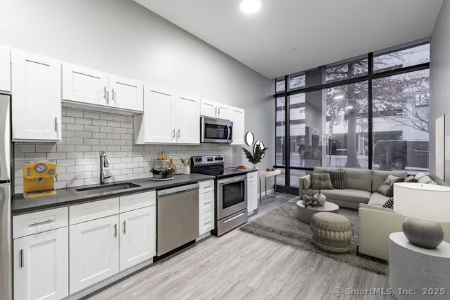 333 State Street, Unit 703 Bridgeport, CT 06604 - Photo 5 of 27 a kitchen with stainless steel appliances granite countertop a stove a sink dishwasher a microwave oven and a dining table with wooden floor