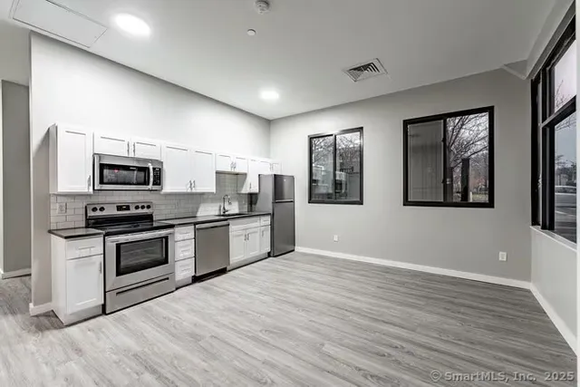 a kitchen with stainless steel appliances granite countertop a stove a sink and a microwave