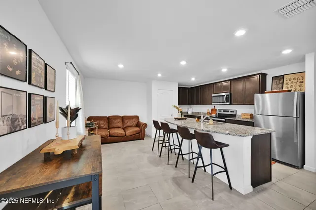 a kitchen with stainless steel appliances kitchen island granite countertop a sink a stove a refrigerator cabinets and chairs