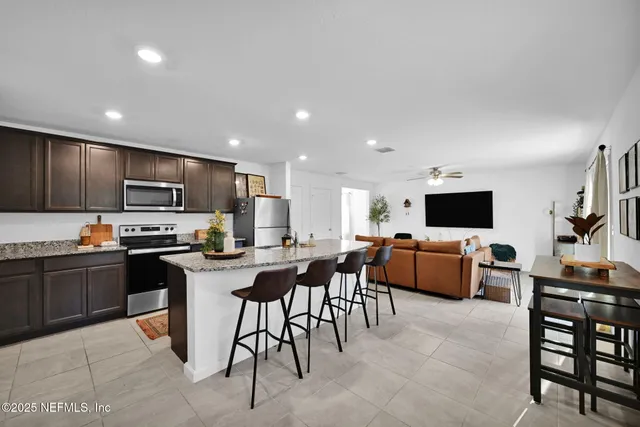 a living room with furniture a flat screen tv and kitchen view