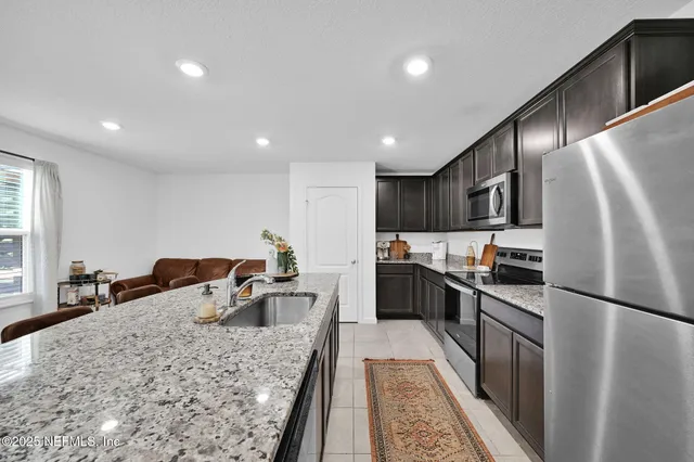 a kitchen with stainless steel appliances granite countertop a refrigerator a stove and a sink with wooden floor