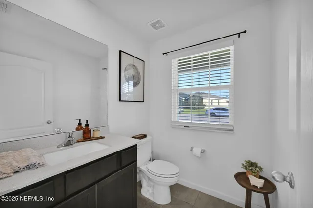 a bathroom with a toilet sink a mirror and a window