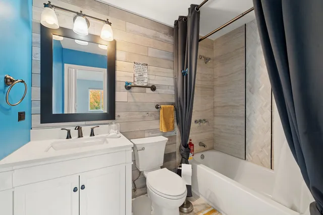 a bathroom with a bathtub shower sink vanity mirror and toilet