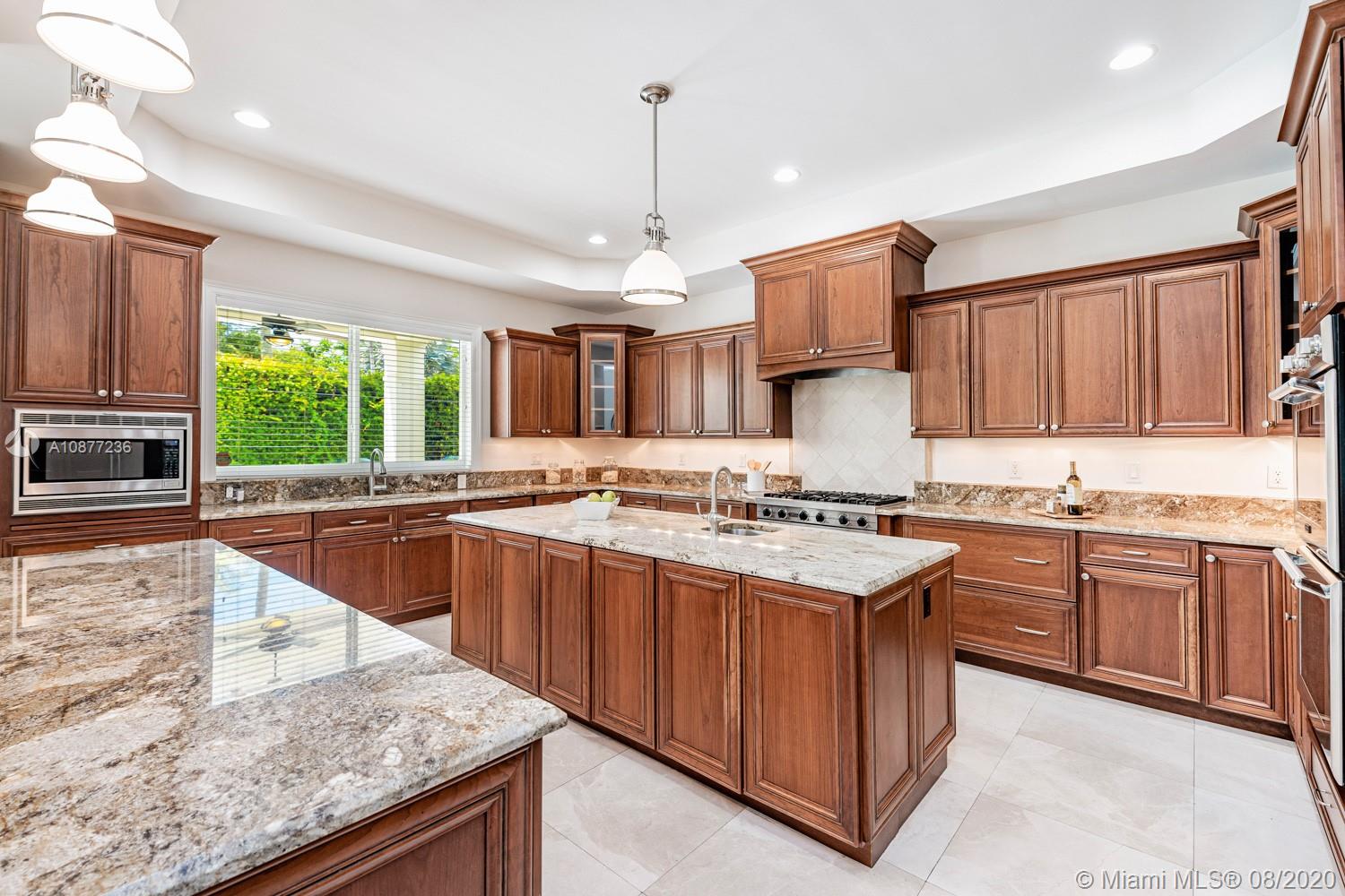 7260 Southwest 119th Street Pinecrest, FL 33156 - Photo 13 of 40 a kitchen with kitchen island granite countertop a sink stove and refrigerator