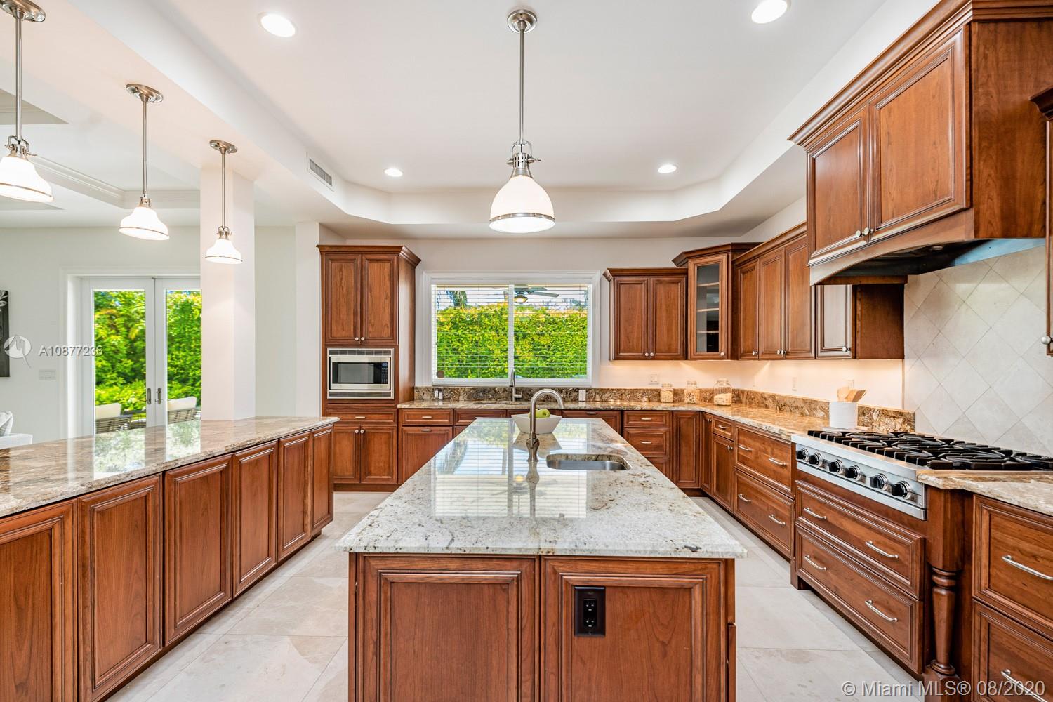 7260 Southwest 119th Street Pinecrest, FL 33156 - Photo 15 of 40 a kitchen with granite countertop stainless steel appliances a stove sink and wooden cabinets