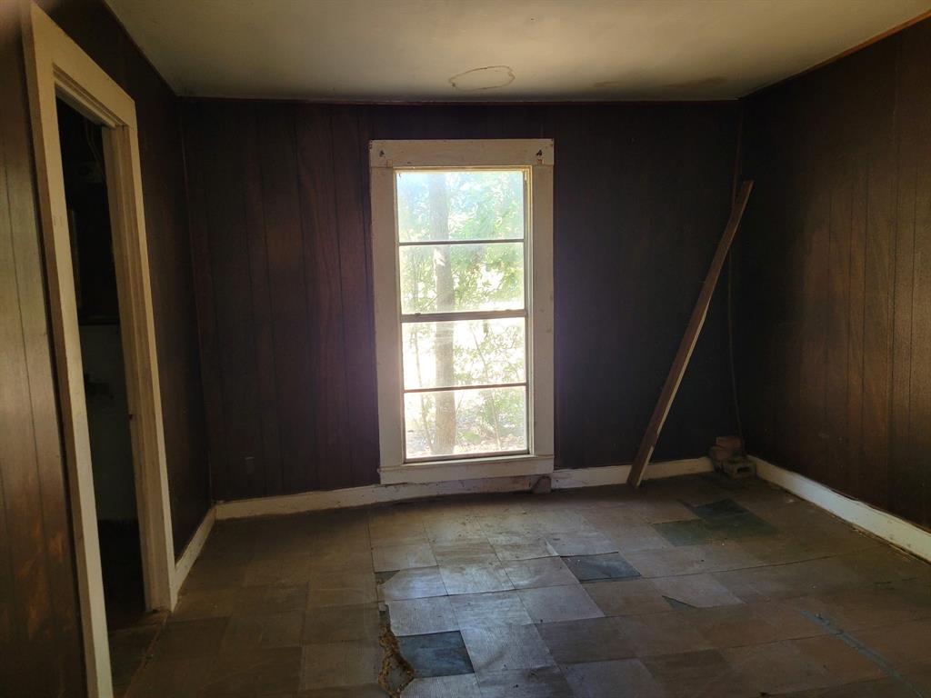 909 Ivan Road Waco, TX 76706 - Photo 4 of 10 Room featuring a single-pane window, dark wood-paneling walls, and an interior doorway with trim