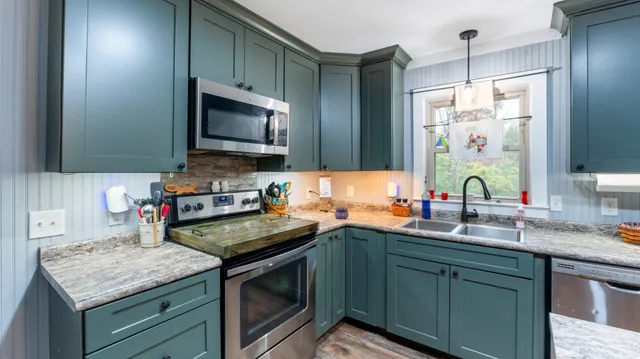 a kitchen with stainless steel appliances granite countertop a sink stove and microwave