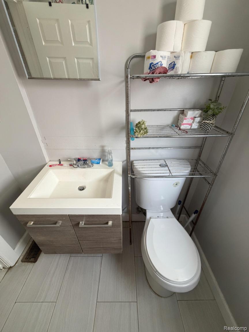 9940 Manor Detroit, MI 48204 - Photo 16 of 16 Bathroom featuring a floating vanity with integrated sink, a white toilet, and light gray tile flooring