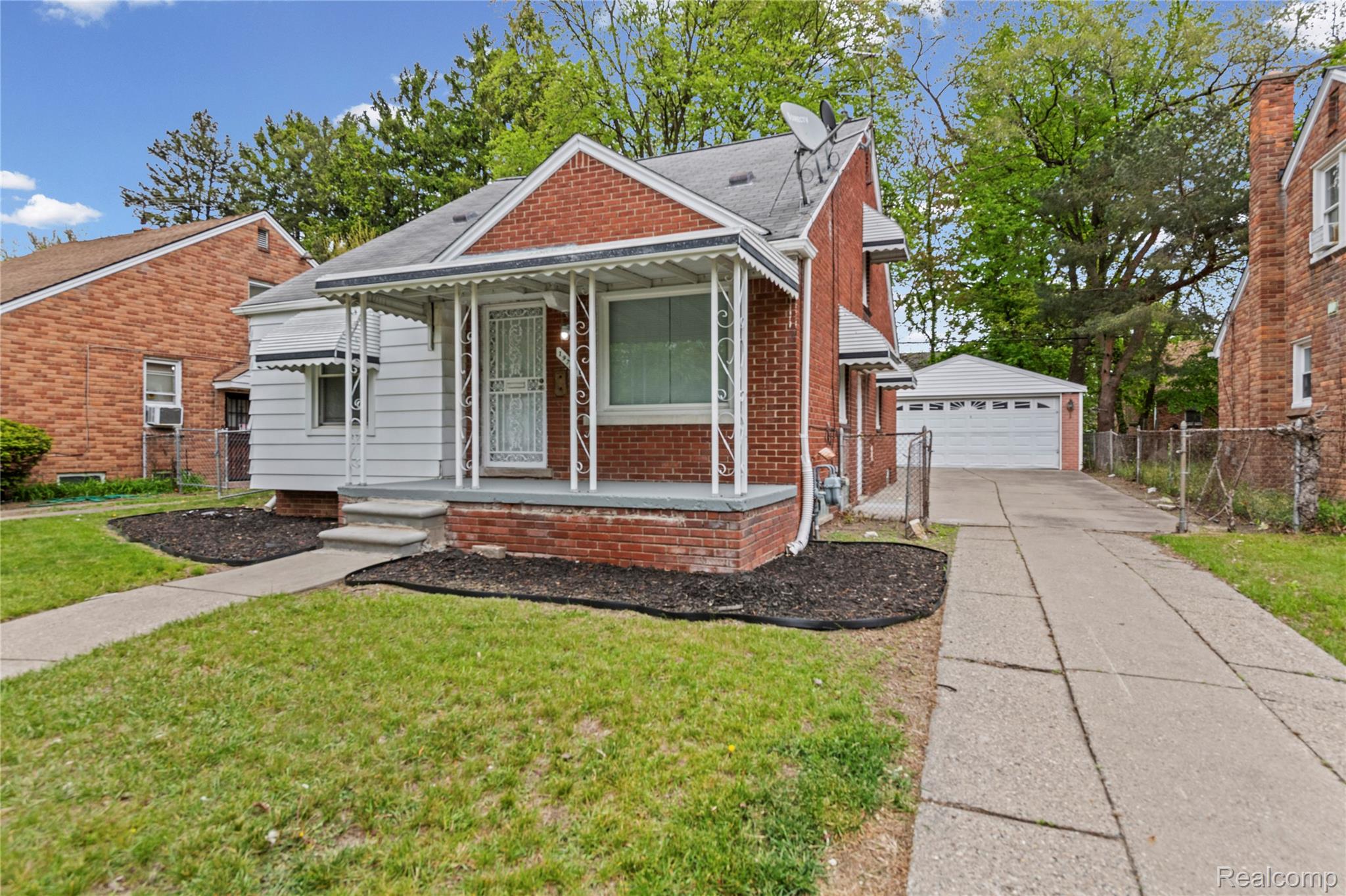 Bungalow featuring a garage, covered porch, and brick siding