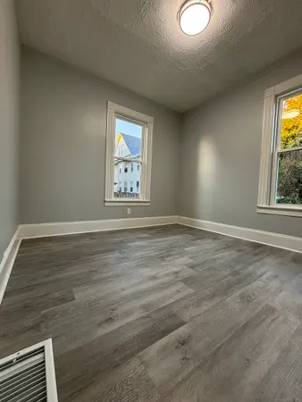 a view of empty room with window and wooden floor