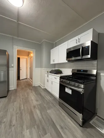 a kitchen with stainless steel appliances a stove a microwave and white cabinets
