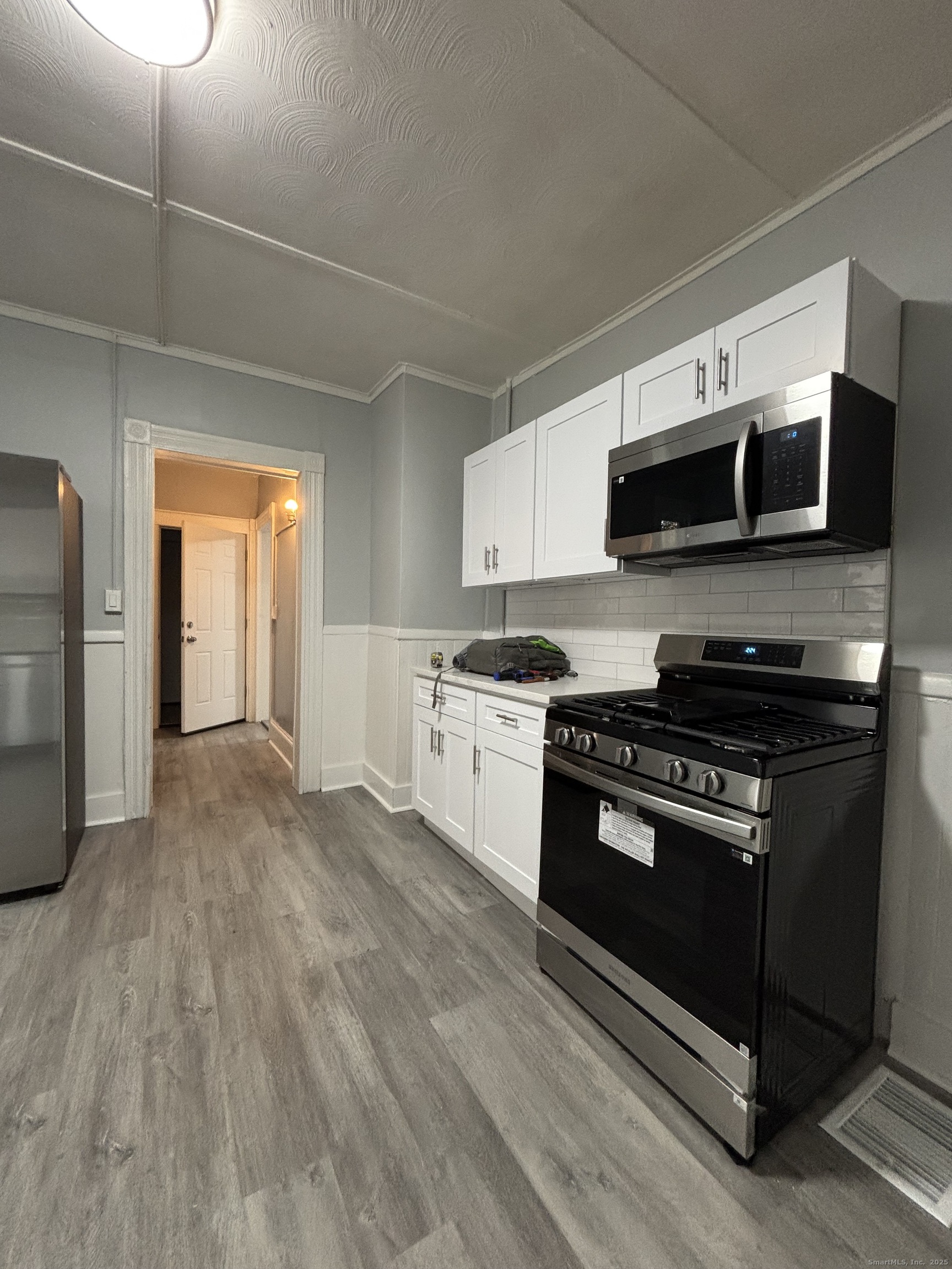 Undisclosed Address Bridgeport, CT 06605 - Photo 18 of 18 a kitchen with stainless steel appliances a stove a microwave and white cabinets
