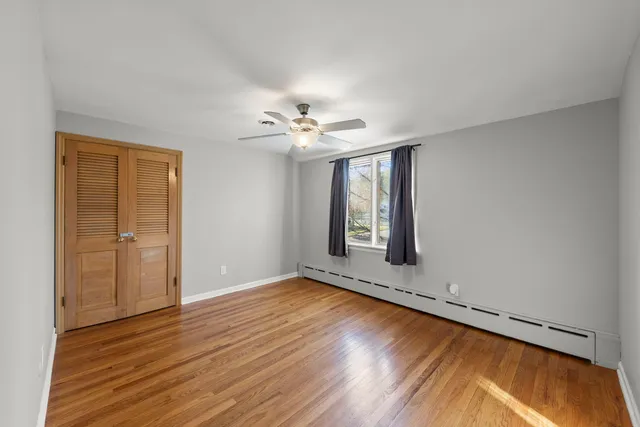 a view of an empty room with window and wooden floor
