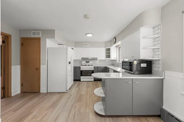 a living room with stainless steel appliances kitchen island granite countertop a sink a stove a refrigerator cabinets and a dining table