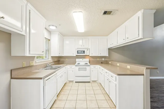 a kitchen with white cabinets appliances and a sink