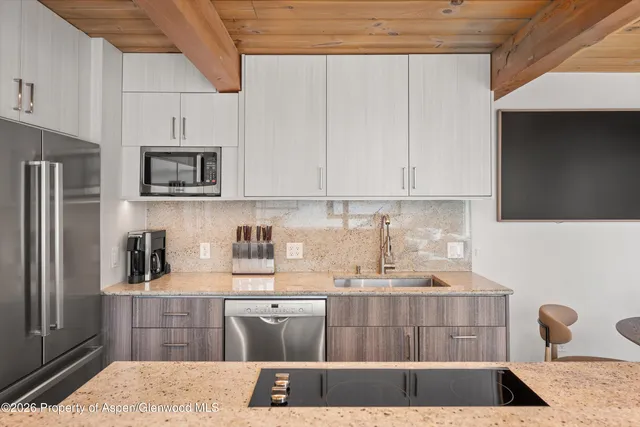 a kitchen with kitchen island granite countertop a refrigerator oven a sink dishwasher and cabinets with wooden floor