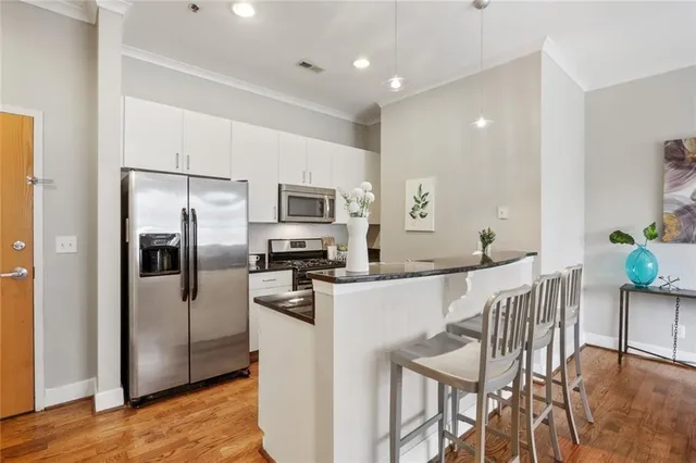 a kitchen with stainless steel appliances a refrigerator a stove a dining table and chairs