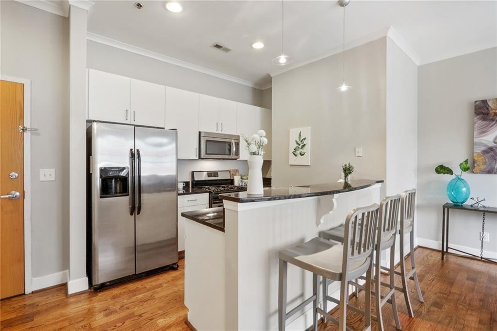 a kitchen with stainless steel appliances a refrigerator a stove a dining table and chairs