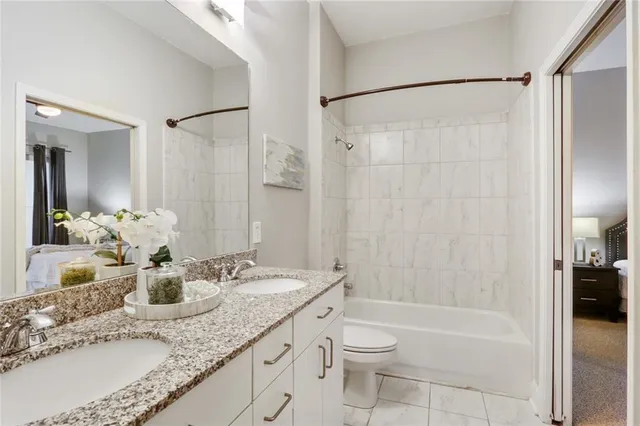 a bathroom with a granite countertop sink a toilet and shower