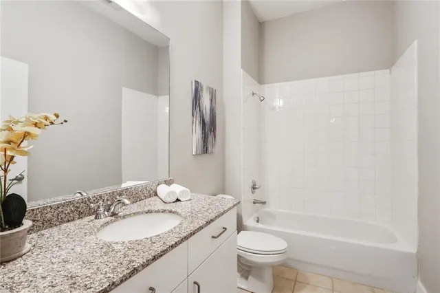 a bathroom with a granite countertop sink a toilet a mirror and shower