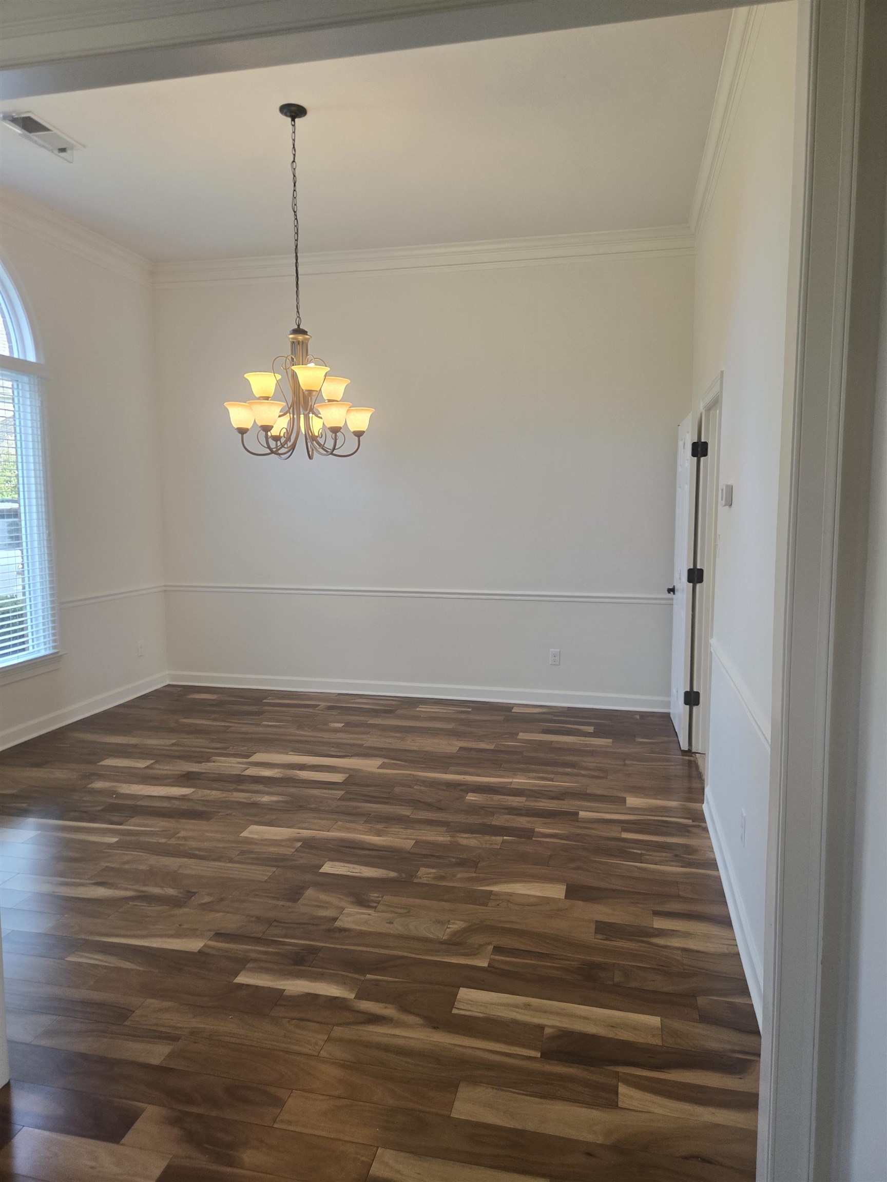 737 Steeple Ridge Cove Collierville, TN 38017 - Photo 8 of 21 Spacious room featuring wood-finish flooring, crown molding, chair rail, and an ornate chandelier