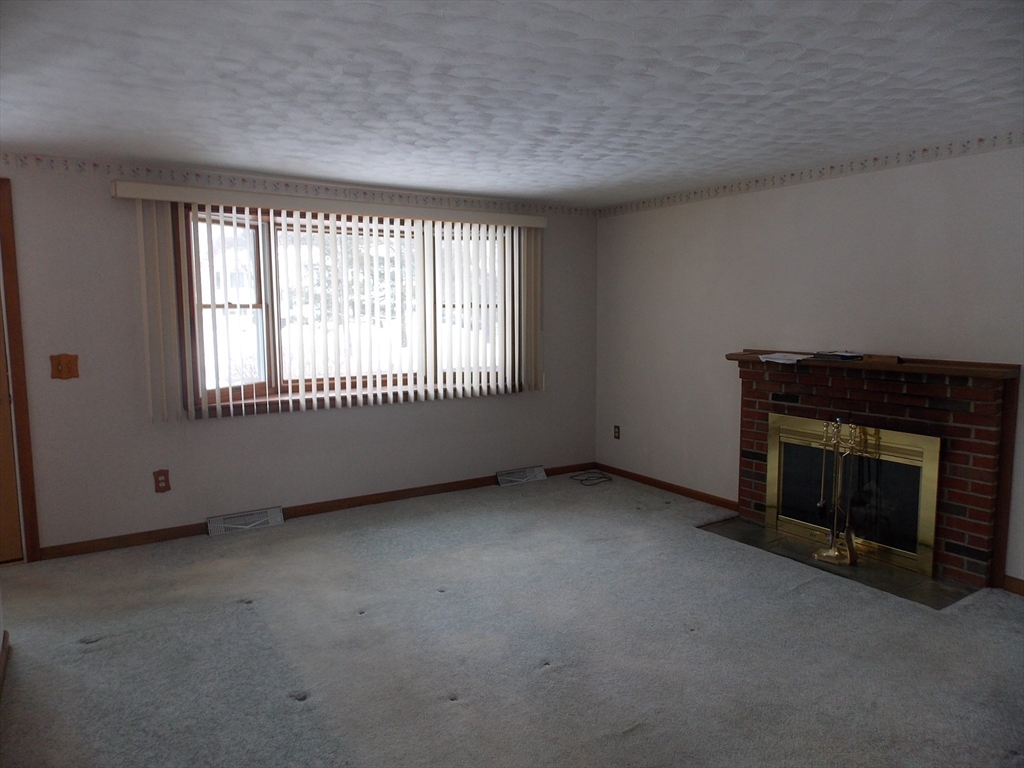 26 Old Bolton Road Hudson, MA 01749 - Photo 8 of 19 a view of an empty room with a fireplace and a window