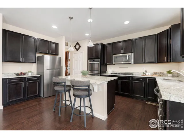 a kitchen with kitchen island granite countertop stainless steel appliances and wooden cabinets