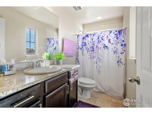 a bathroom with a granite countertop sink a toilet a mirror and shower curtain