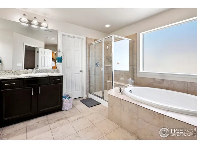 a spacious bathroom with a tub sink and mirror