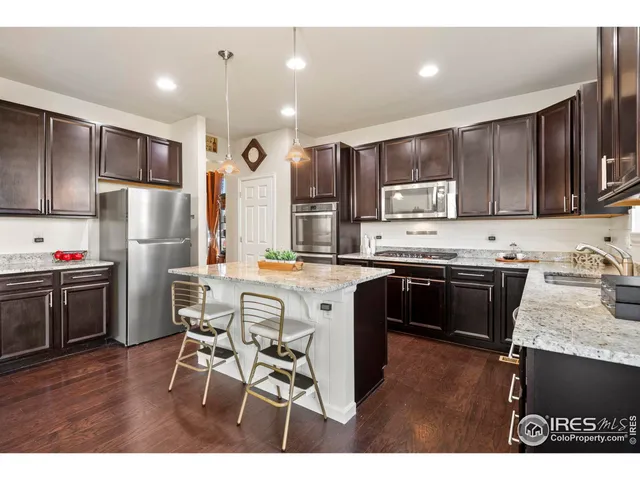 a kitchen with stainless steel appliances kitchen island granite countertop a refrigerator a stove a sink a dining table and chairs