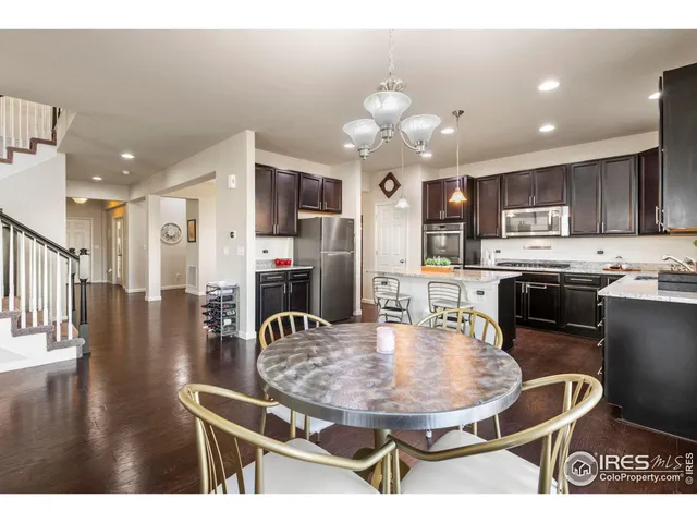 a kitchen with stainless steel appliances kitchen island granite countertop a sink a stove a kitchen island with chairs and wooden floor