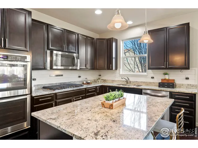 a kitchen with kitchen island granite countertop wooden cabinets and stainless steel appliances