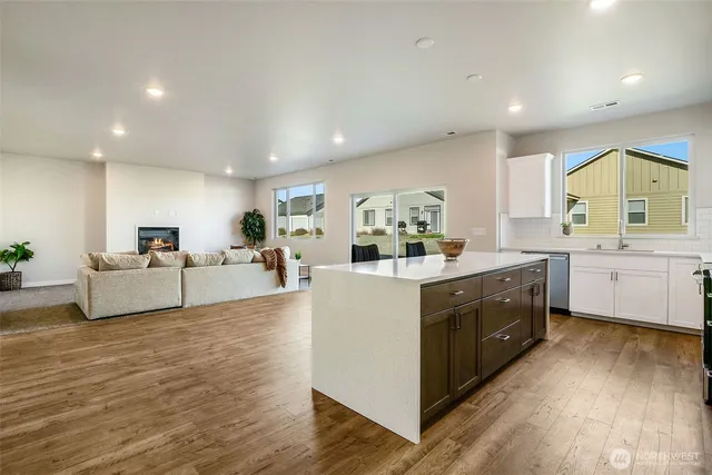 a kitchen with stainless steel appliances granite countertop a stove a sink a refrigerator and white cabinets