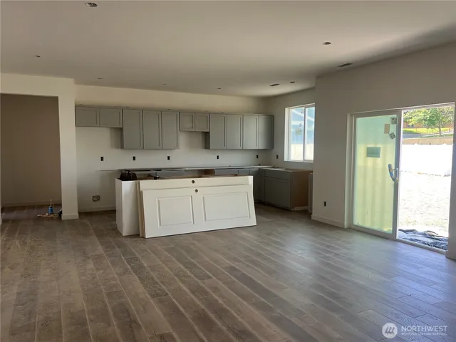 a large kitchen with stainless steel appliances granite countertop a stove top oven a sink dishwasher and a refrigerator with wooden floor