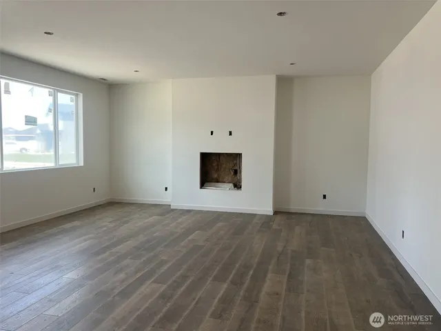 an empty room with windows and fireplace