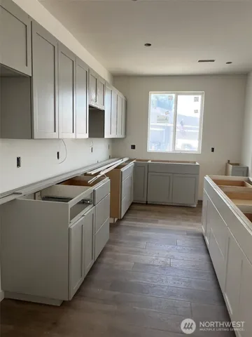 a large kitchen with stainless steel appliances granite countertop a sink and dishwasher a stove top oven with wooden floor