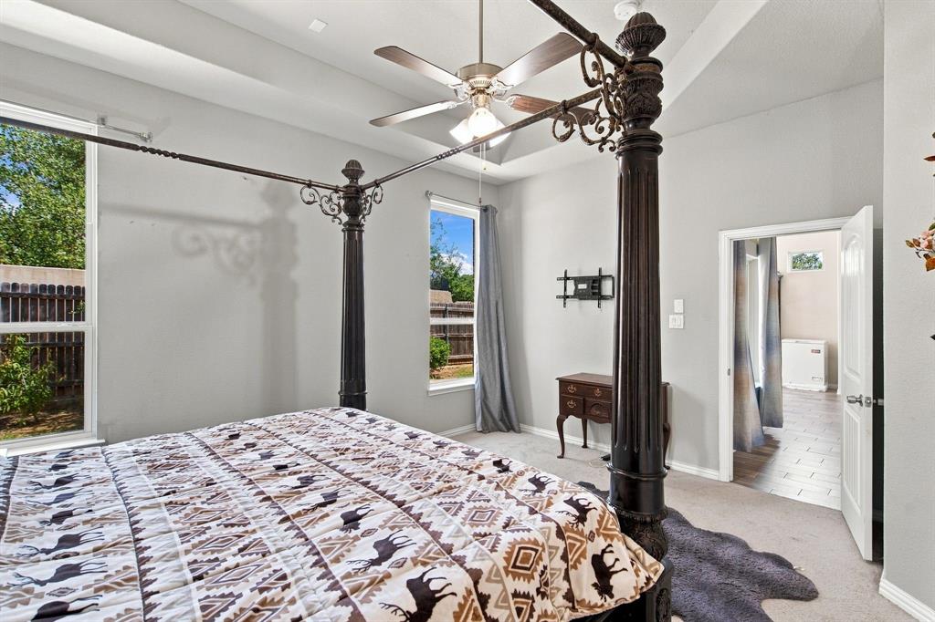 3908 Ranchman Boulevard Denton, TX 76210 - Photo 13 of 29 Tray ceiling with a ceiling fan, two large windows, and light gray wall paint