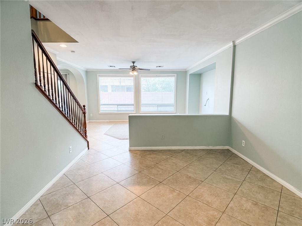 8683 Moreno Mountain Avenue Las Vegas, NV 89178 - Photo 2 of 26 A well-lit living area features tiled flooring and a prominent staircase leading to the upper level.