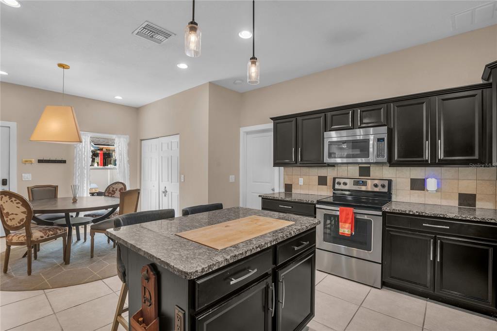 2414 Newberry Street Orlando, FL 32806 - Photo 14 of 36 a kitchen with stainless steel appliances granite countertop a stove top oven a sink dishwasher a dining table and chairs with wooden floor