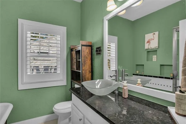 a bathroom with a granite countertop toilet a sink and a mirror