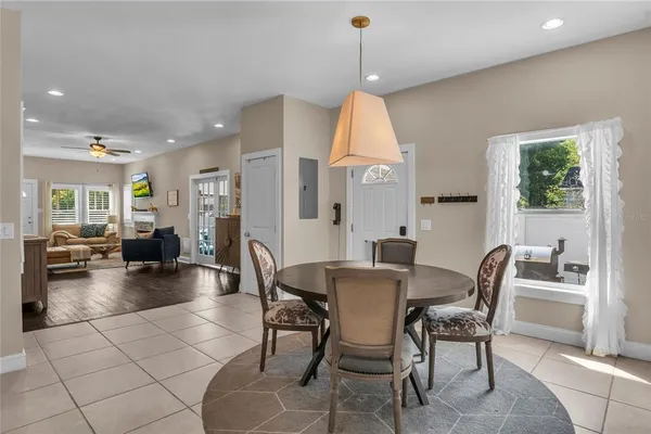 a view of a dining room and livingroom with furniture wooden floor a rug a fireplace and a chandelier