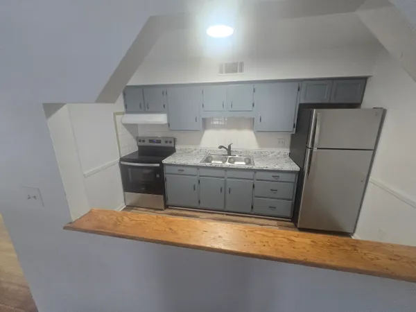a kitchen with stainless steel appliances granite countertop a refrigerator a stove and a sink