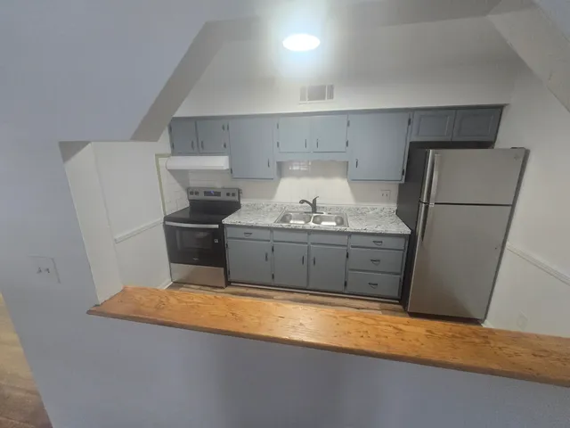 a kitchen with stainless steel appliances granite countertop a refrigerator a stove and a sink