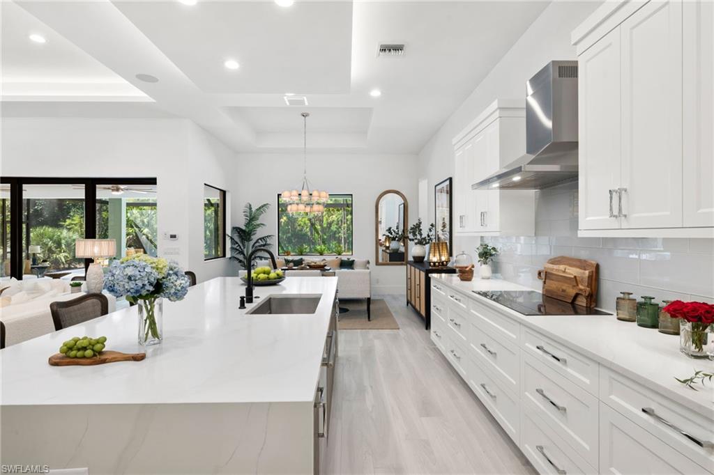4221 7th Avenue Northwest Naples, FL 34119 - Photo 9 of 42 a large white kitchen with lots of counter space and living room view