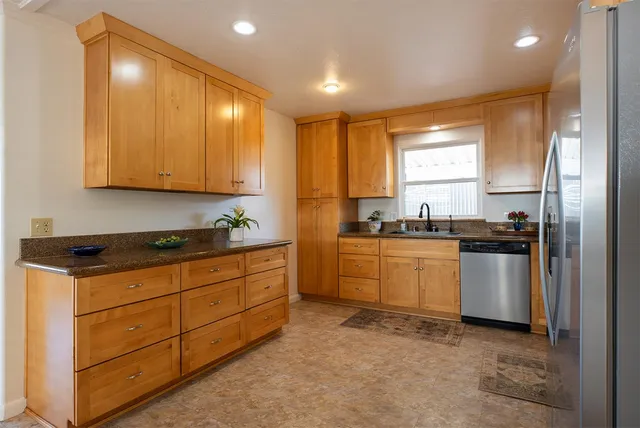 a kitchen with granite countertop a sink cabinets stainless steel appliances and a window